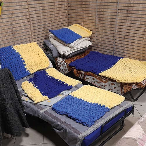 Make shift beds covered with knitted blankets in the blue and yellow colours of the Ukraine flag