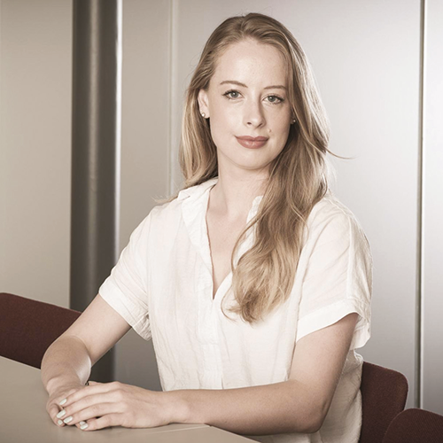 A portrait of Catriona sitting at a meeting table with her hands crossed on the table